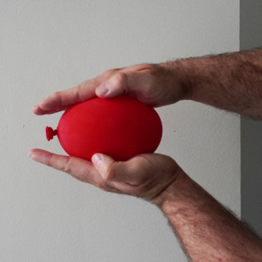 Photo of a red balloon between two hands.