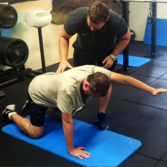 Photo of coaching a client through the level 1 Bird-Dog variation.